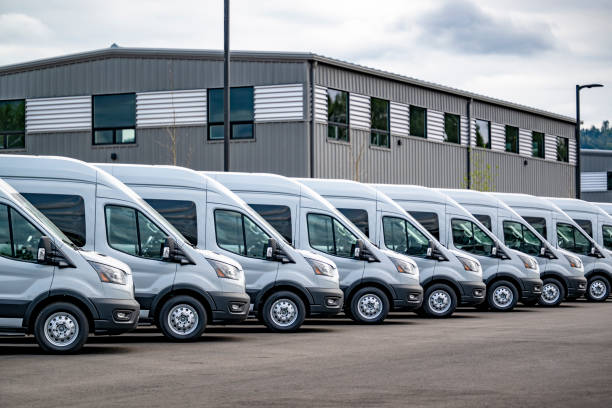 Industrial grade popular gray compact cargo mini vans for use for small business and local deliveries standing in row on warehouse parking lot waiting for the next local deliveries